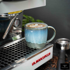 PHENIOX Cappuccino Tasse Ocean steht unter einer Siebträgermaschine. Es ist tolles Latte Art in der Tasse.