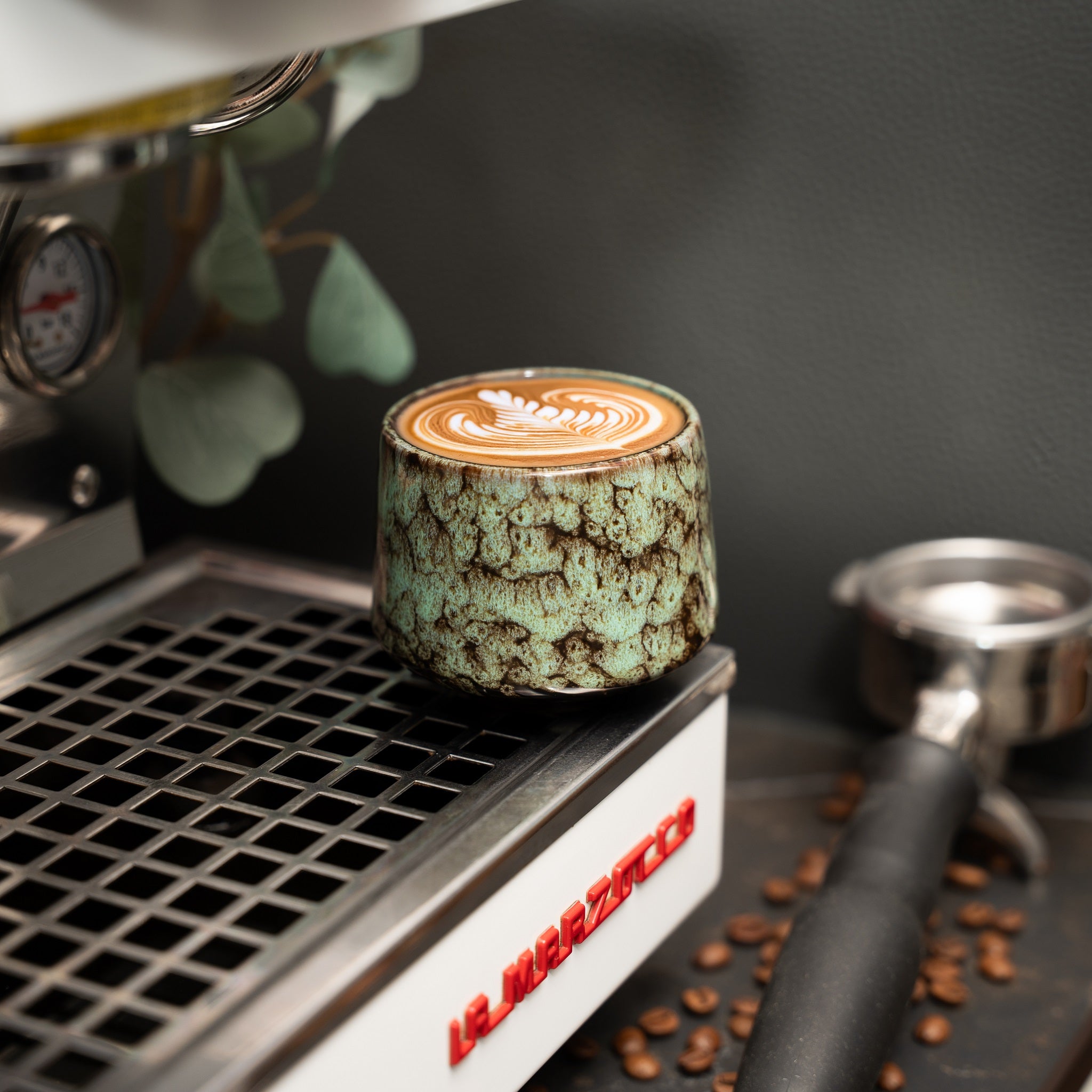 Cappuccino Tasse auf einer Siebträgermaschine mit Latte Art darin.