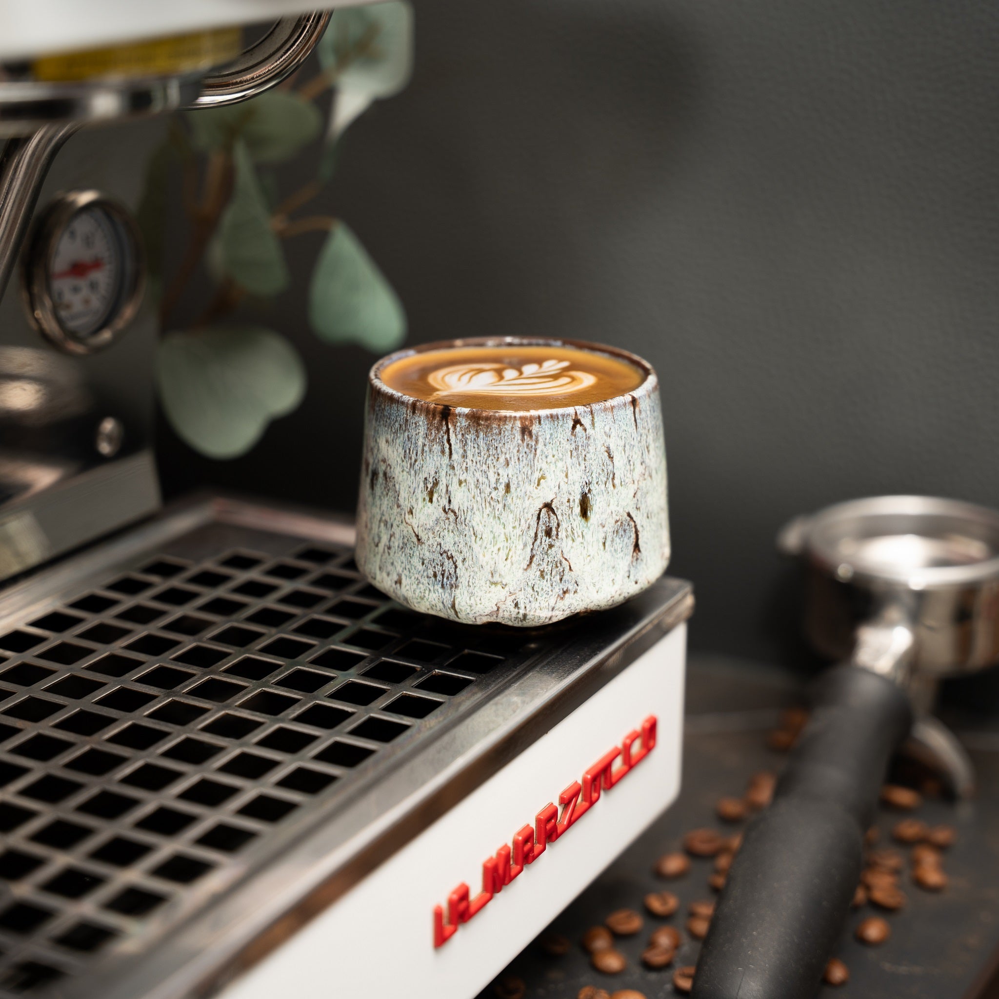 Cappuccino Tasse auf einer Siebträgermaschine mit Latte Art darin.