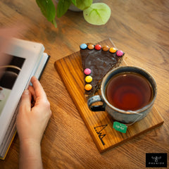 PHENIOX Teetasse Infinity XL gefüllt mit Tee steht auf einem Holzbrettchen zusammen mit einem Stück Kuchen.